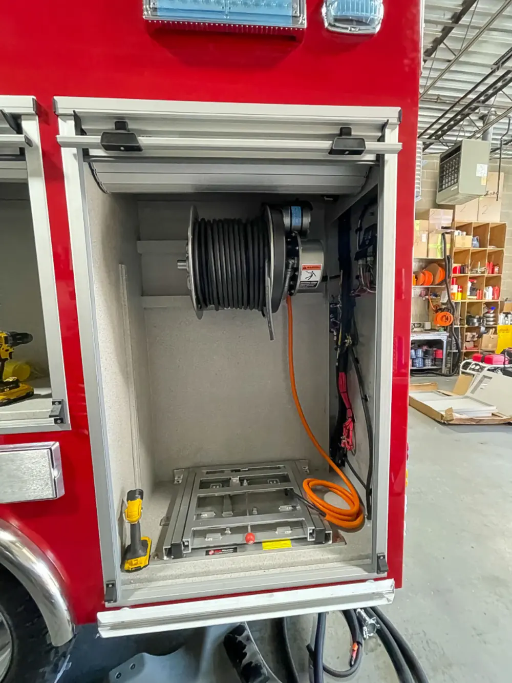 Exterior view of small fire truck showing cab, body compartments, and wheel/tire area.